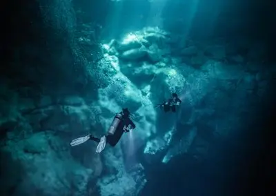 Diver in The Pit cenote with sunlight beams