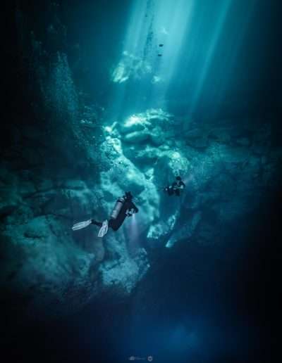 Diver in The Pit cenote with sunlight beams